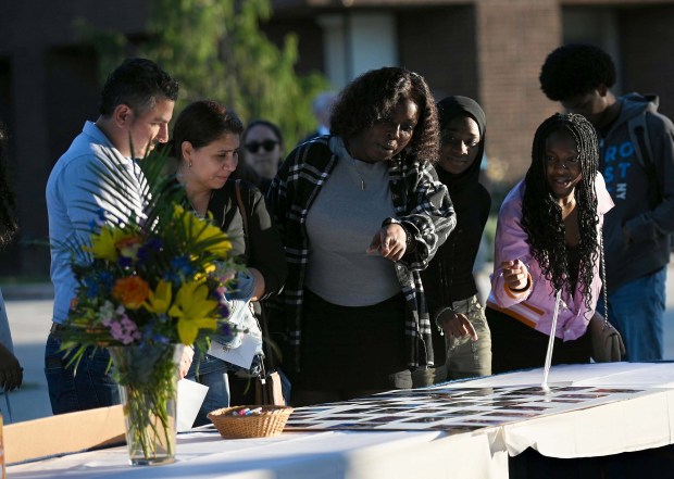 Students and Manuel Albornoz, the uncle of Andrea Rodriguez Avila, left, look at memorial picture boards at the vigil at CCBC-Essex for Andrea Rodriguez Avila, who died in the Rice University shooting. (Kenneth K. Lam/staff)