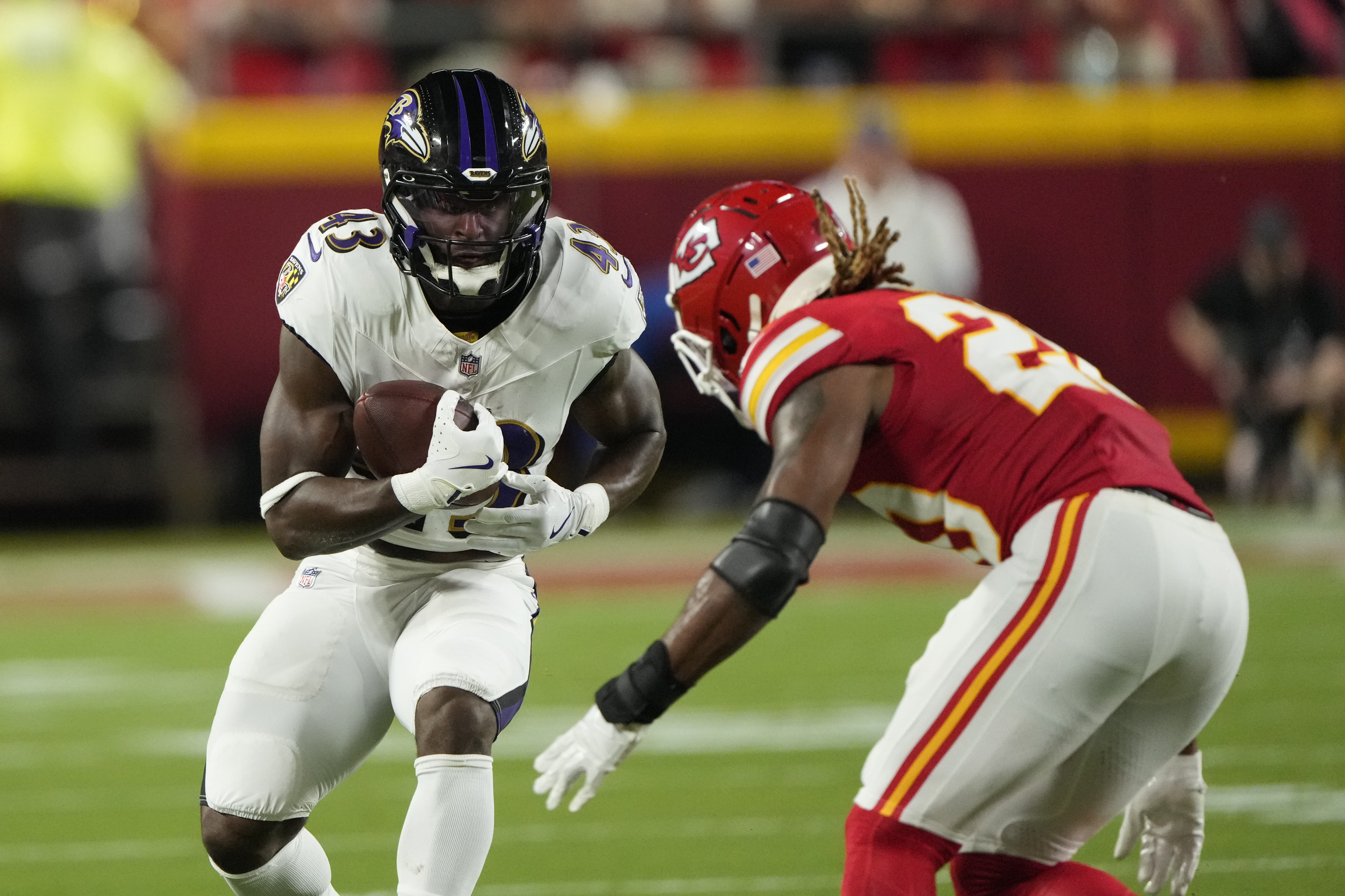 Baltimore Ravens running back Justice Hill (43) runs with the ball as Kansas City Chiefs safety Justin Reid defends during the first half of an NFL football game Thursday, Sept. 5, 2024, in Kansas City, Mo. (AP Photo/Charlie Riedel)